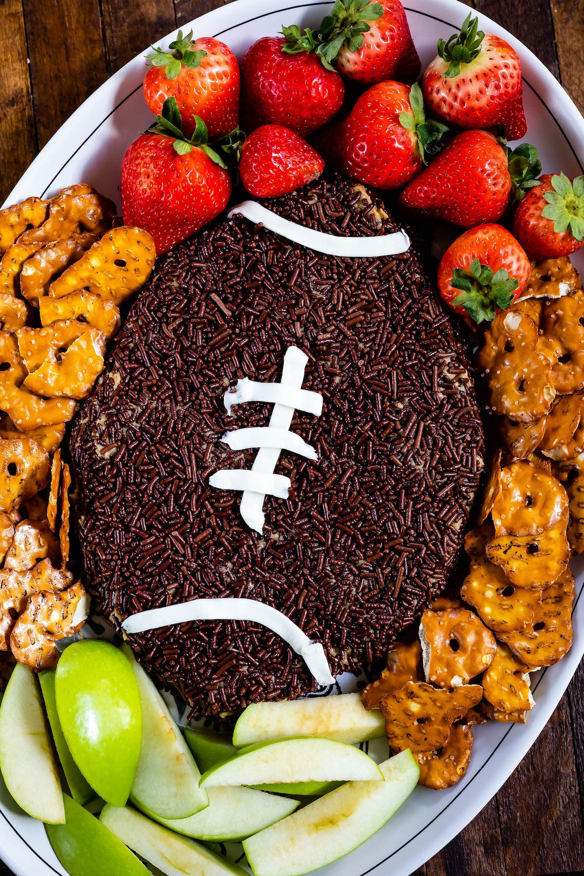football shaped dip with pretzels, strawberries and apples around the edge