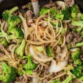 beef, broccoli and other things mixed together in a black pan with words on top