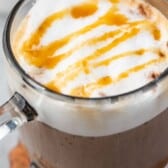 latte in a clear glass with froth and caramel drizzle on top with words on top of the image