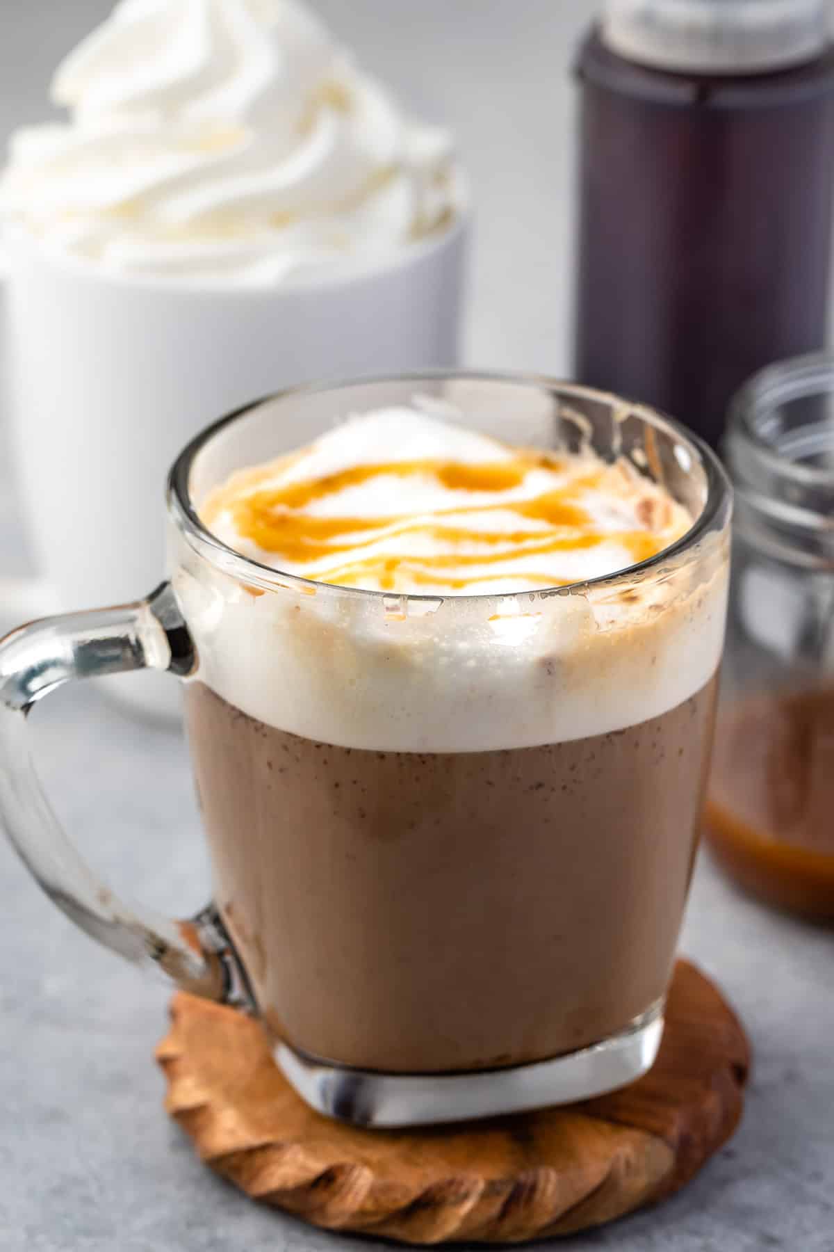 latte in a clear glass with froth and caramel drizzle on top