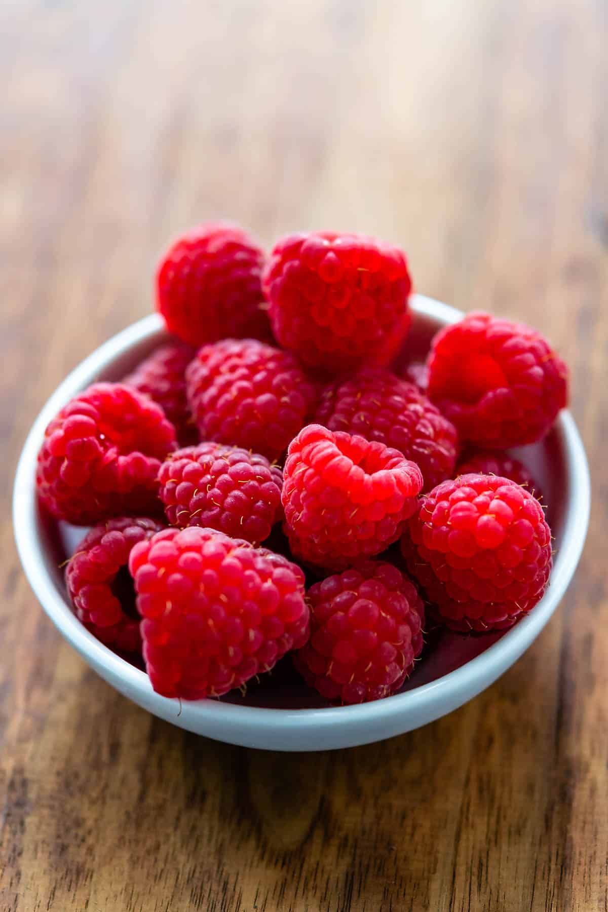 a white bowl of raspberries