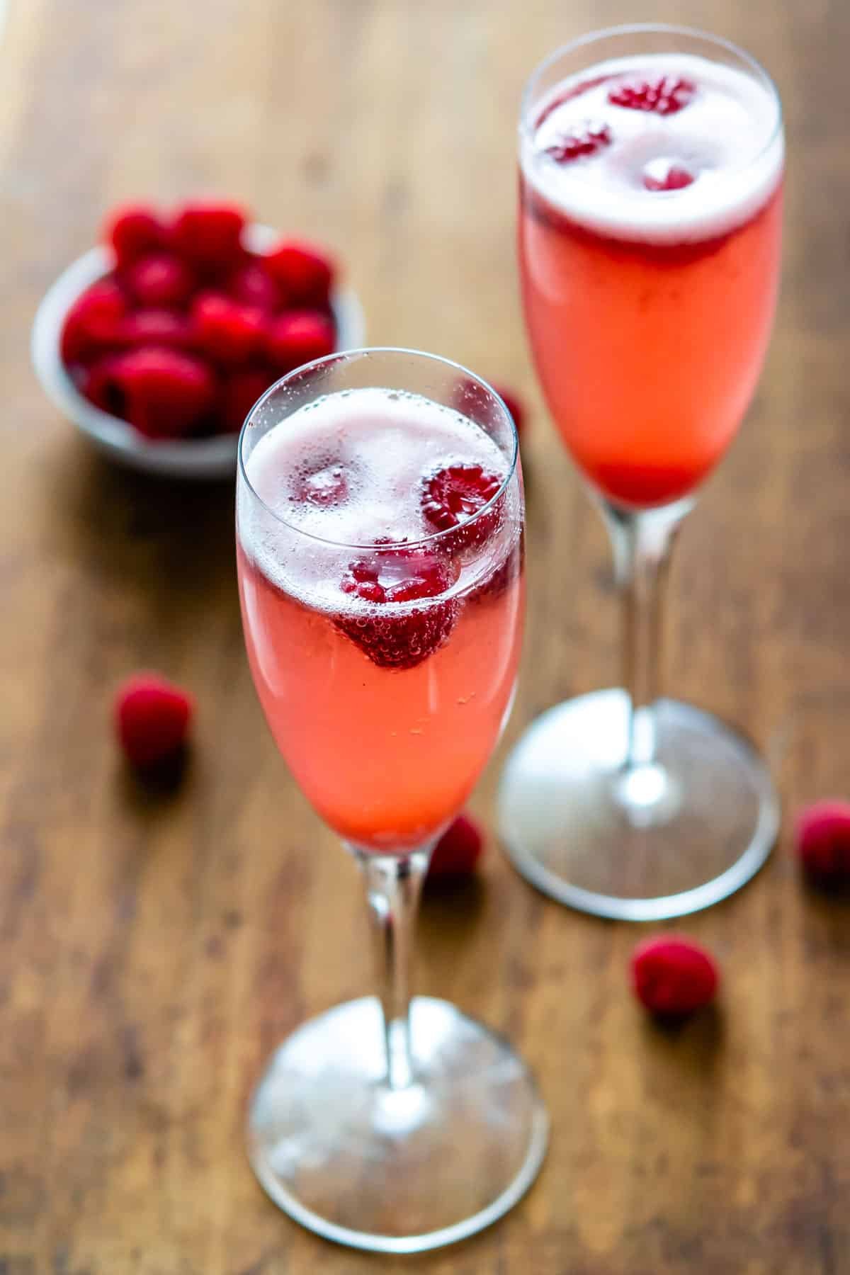 pink drink in a tall glass with raspberries around it