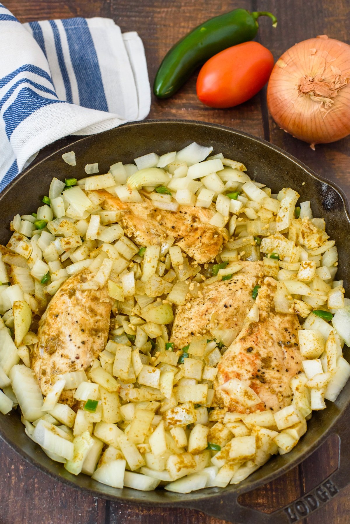 chicken and veggies in a pan with sauce and a spoon