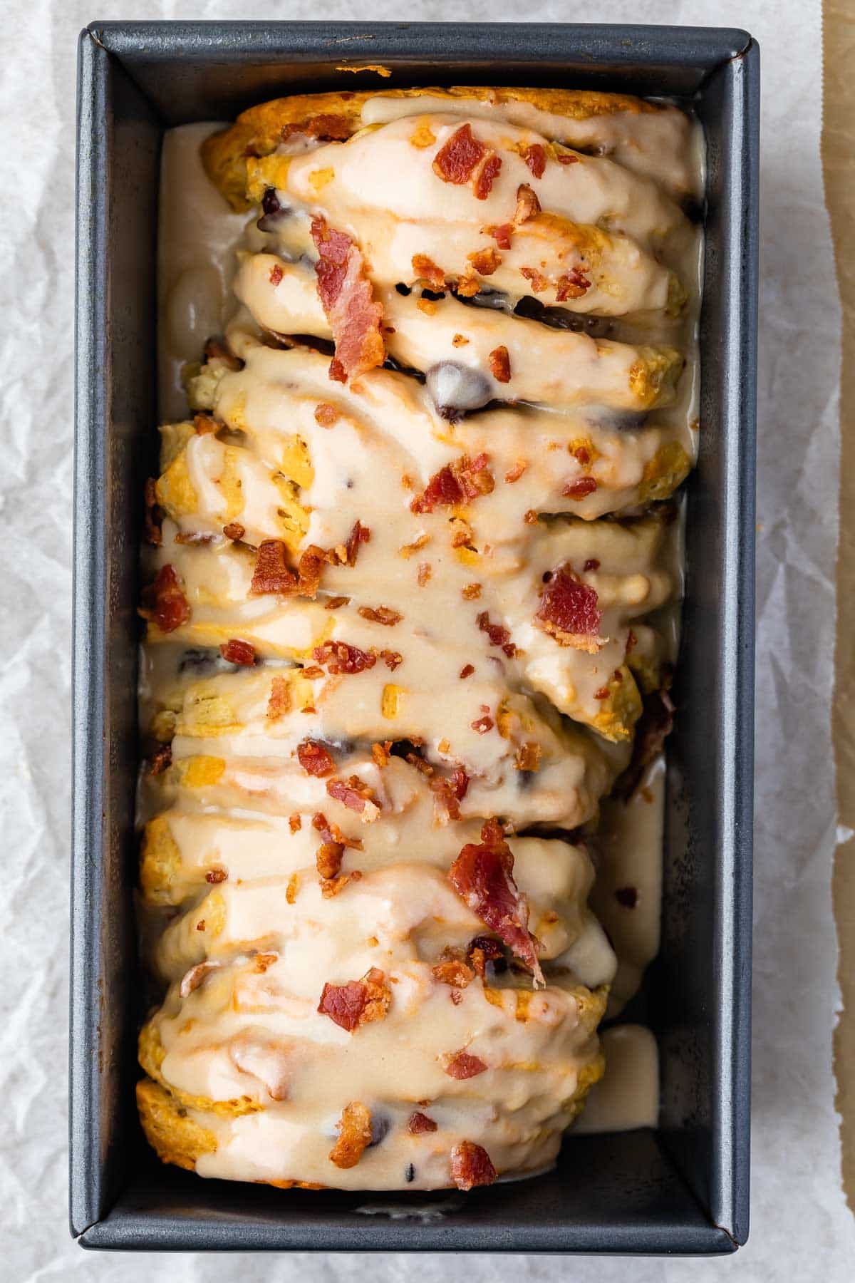 loaf of bacon pull apart bread sitting in a bread pan with bacon sprinkled on top