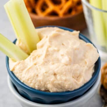 dip in a dark blue and grey bowl with celery sticking out