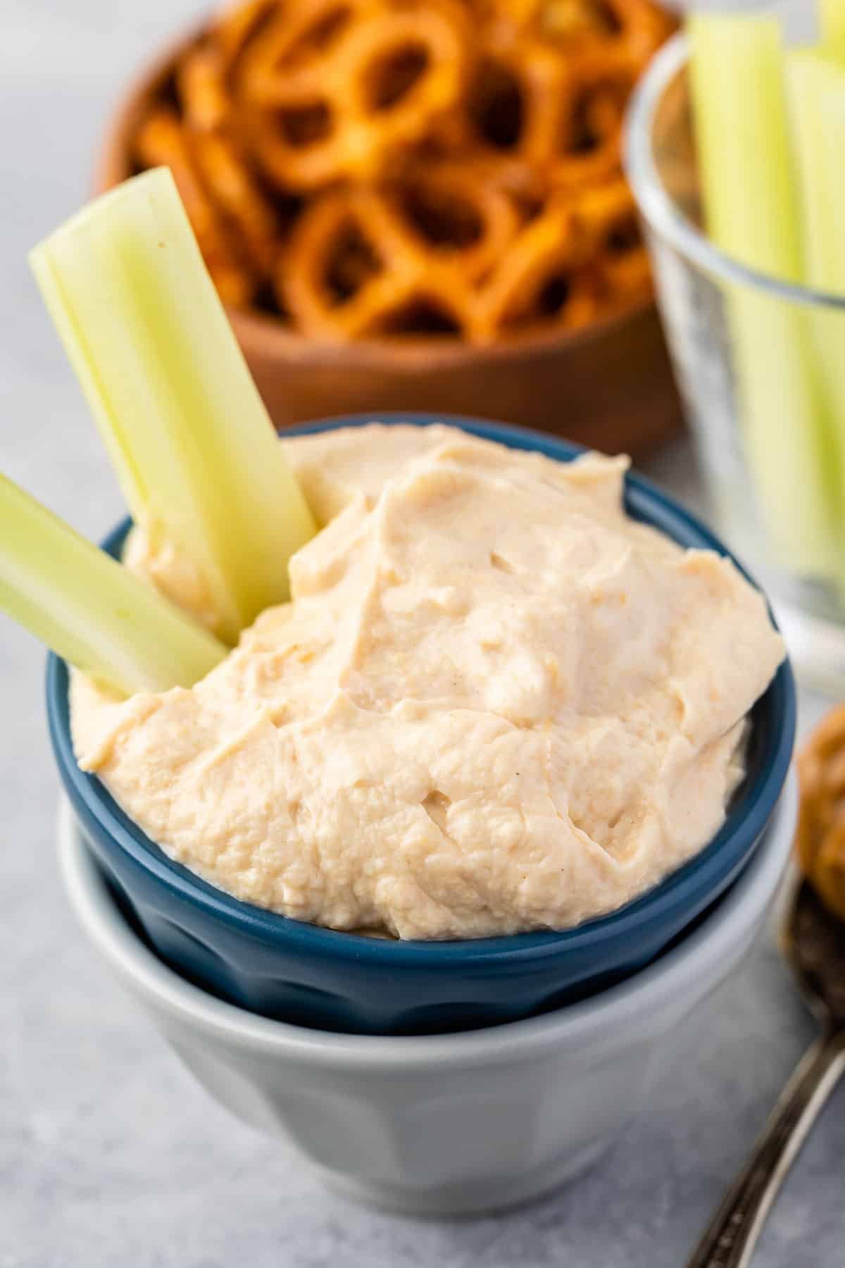 dip in a dark blue and grey bowl with celery sticking out