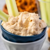 dip in a dark blue and grey bowl with celery sticking out