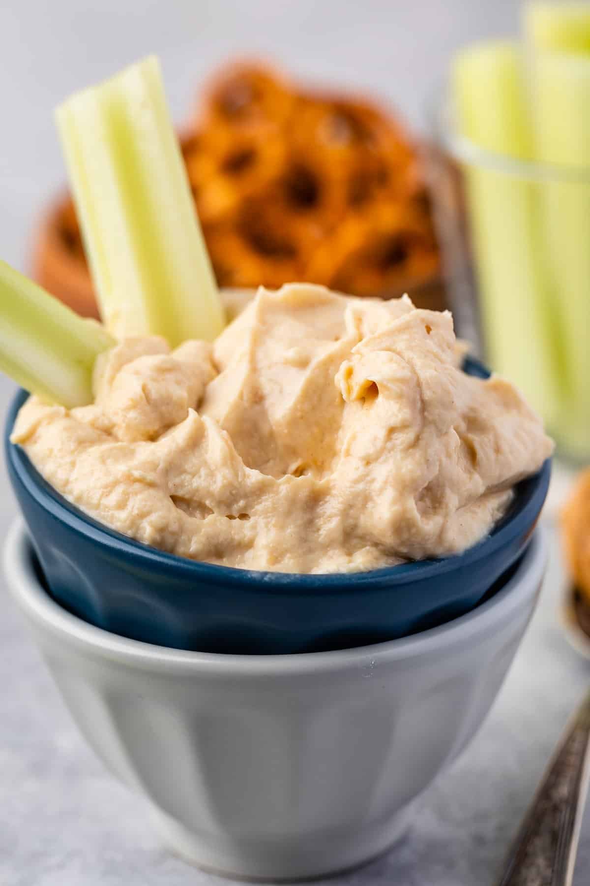 dip in a dark blue and grey bowl with celery sticking out