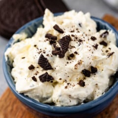 white dip in a blue bowl with Oreos crunched on top