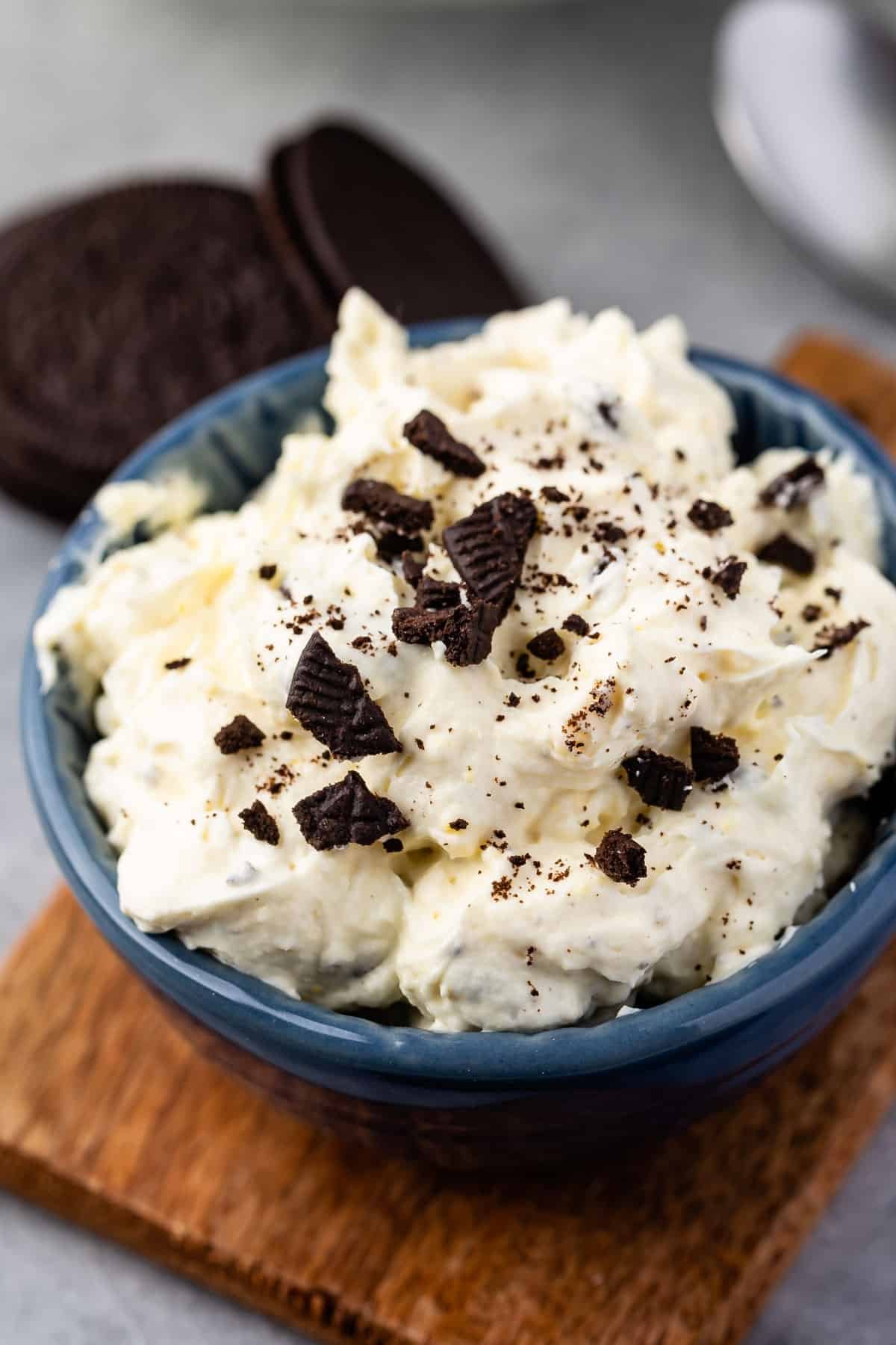 white dip in a blue bowl with Oreos crunched on top