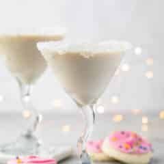 white drink in a a martini glass with sugar cookies around the base of the glass