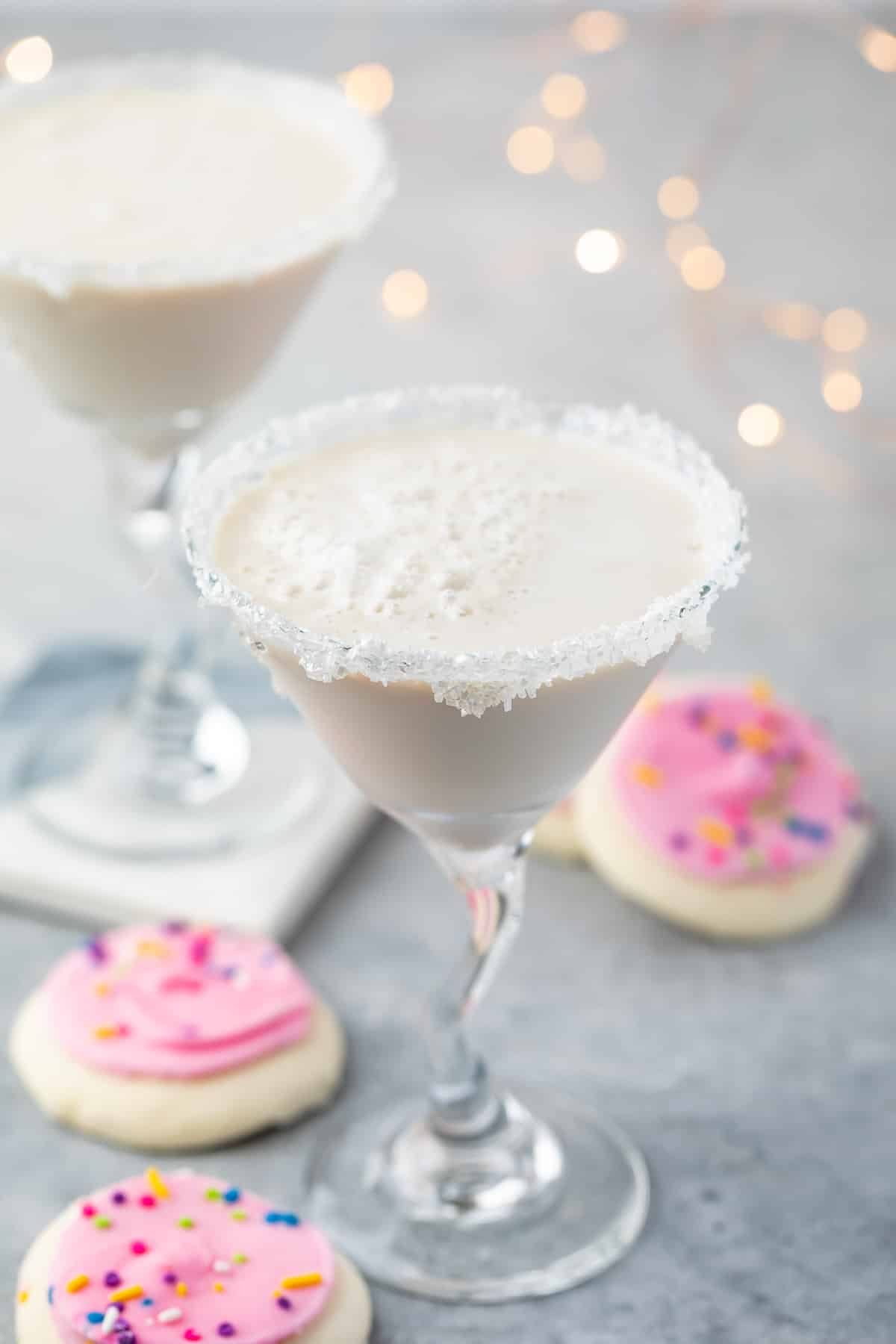 white drink in a a martini glass with sugar cookies around the base of the glass