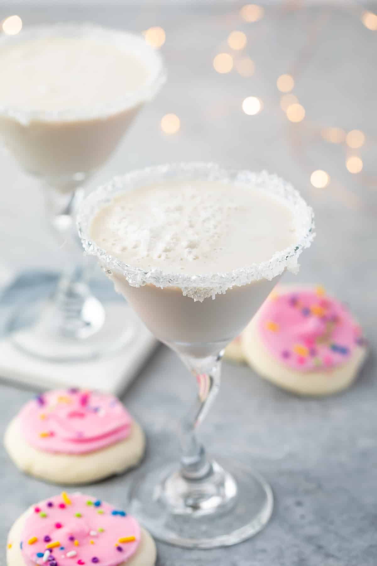 white drink in a a martini glass with sugar cookies around the base of the glass