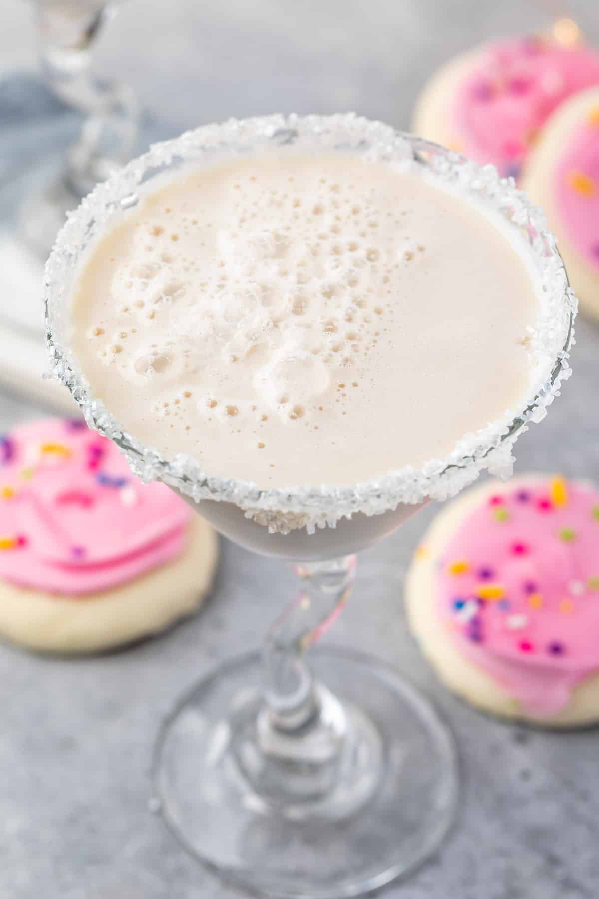 white drink in a a martini glass with sugar cookies around the base of the glass