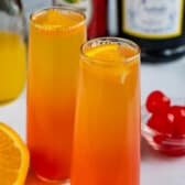 two glasses of orange and red ombre drink inside