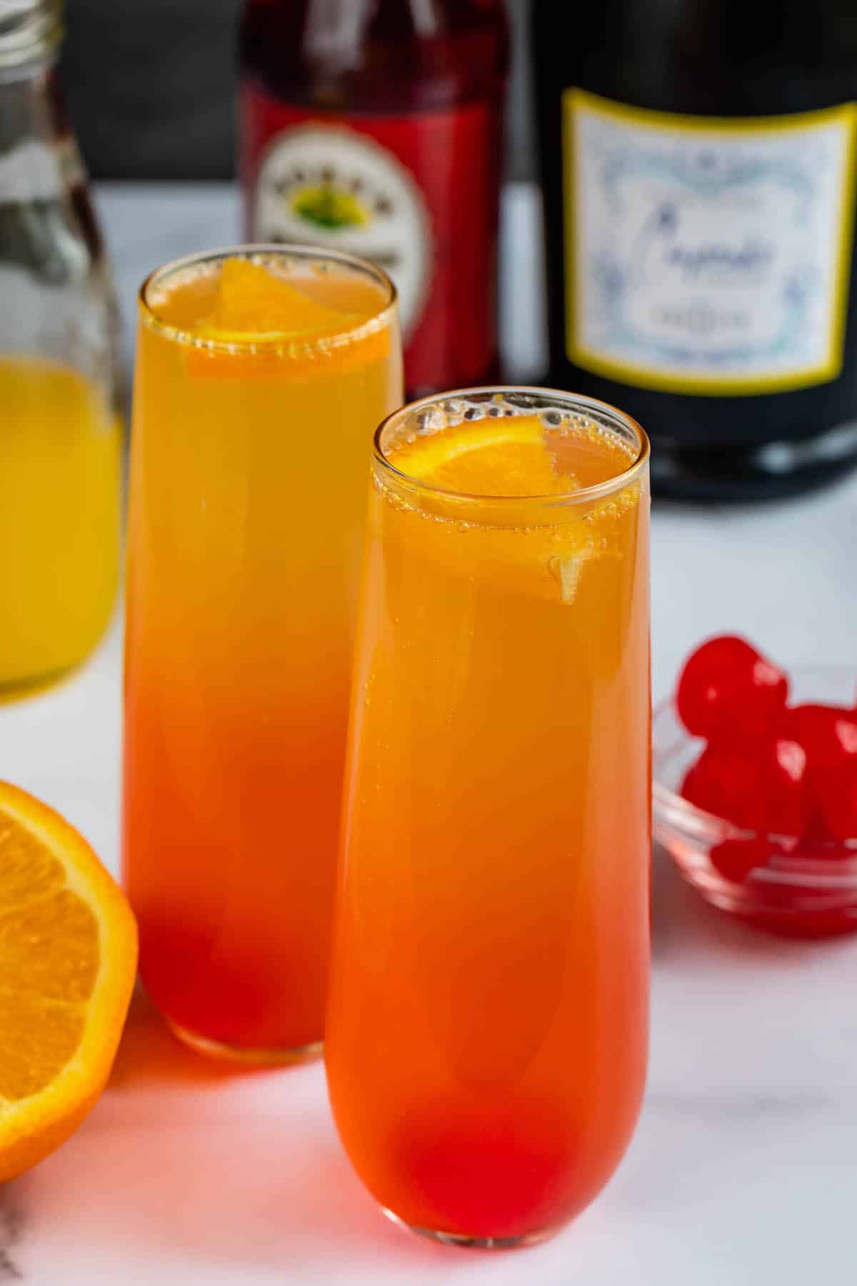 two glasses of orange and red ombre drink inside