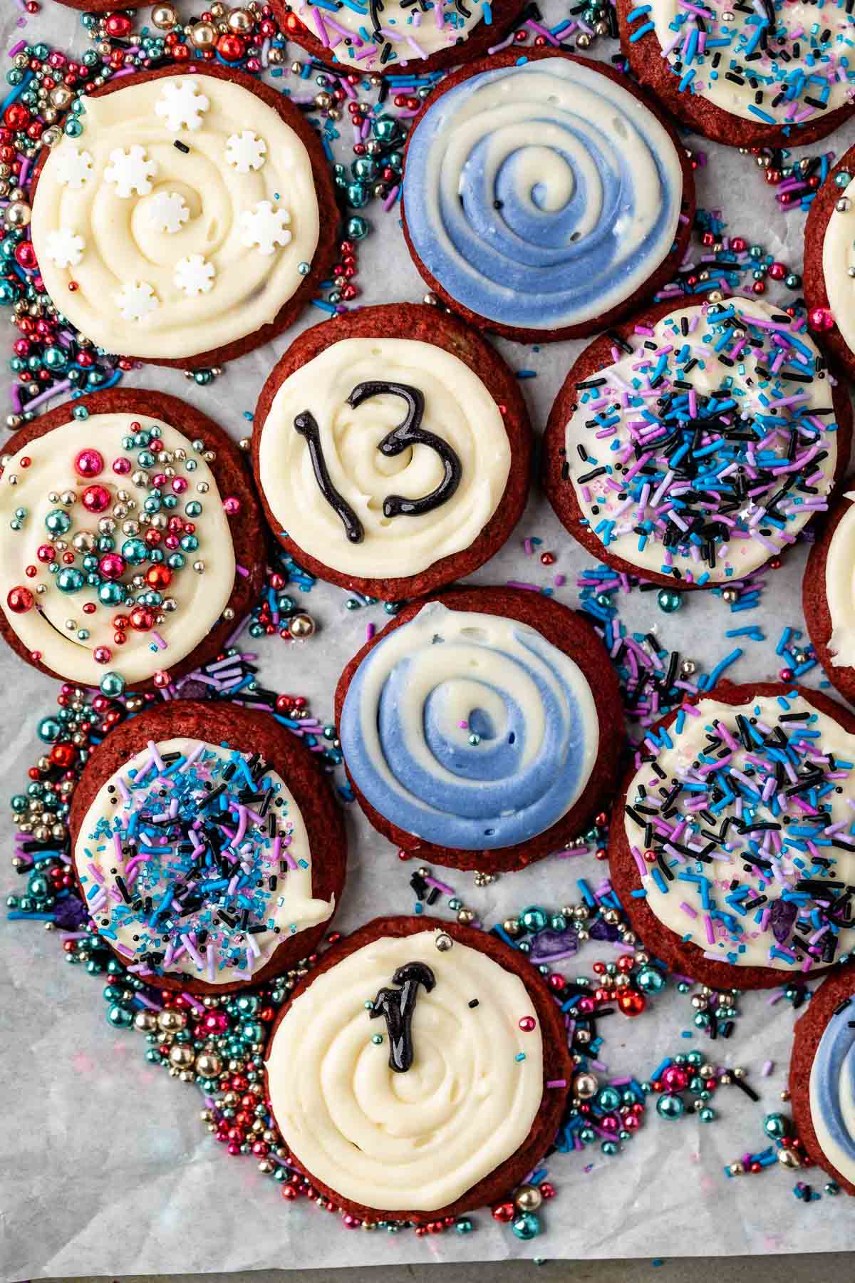 red velvet cookies with white frosting and blue and purple toppings