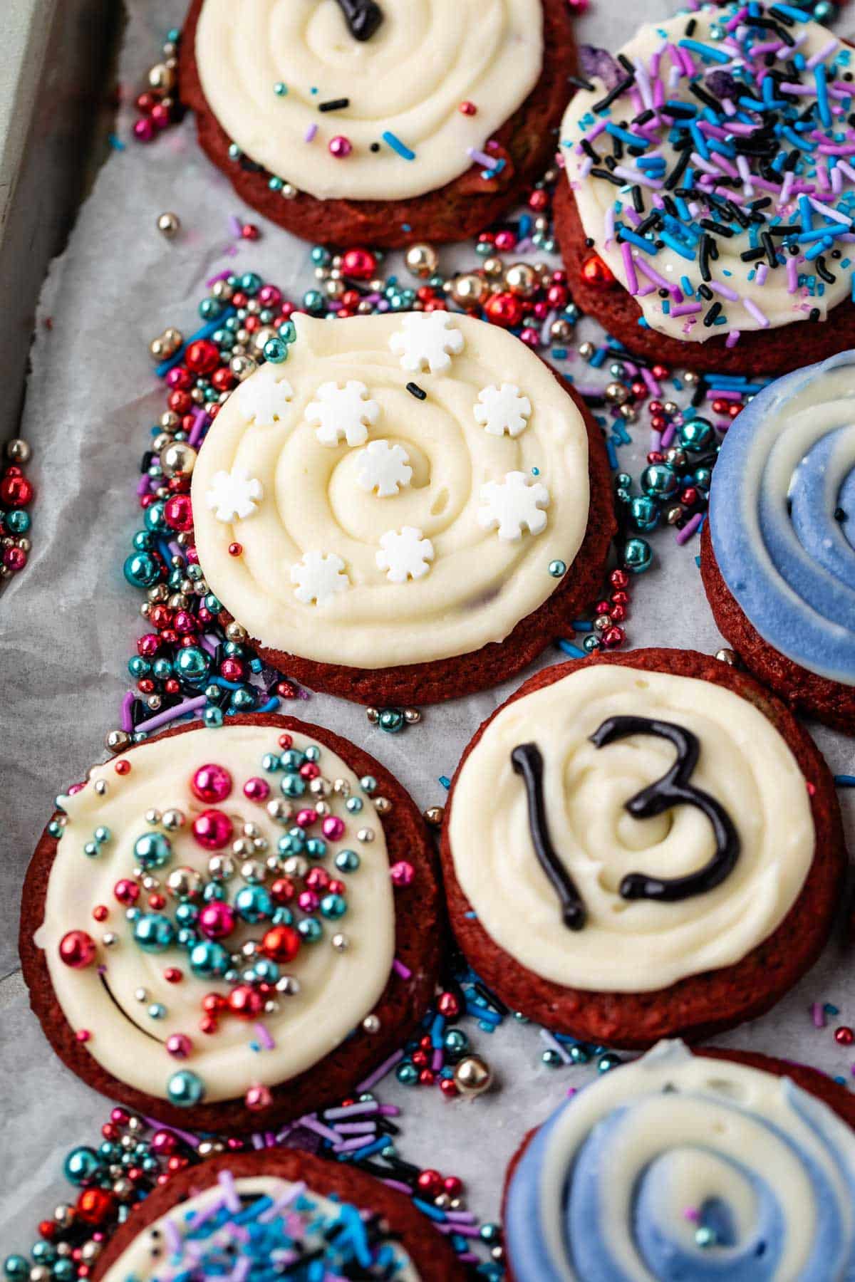 red velvet cookies with white frosting and blue and purple toppings