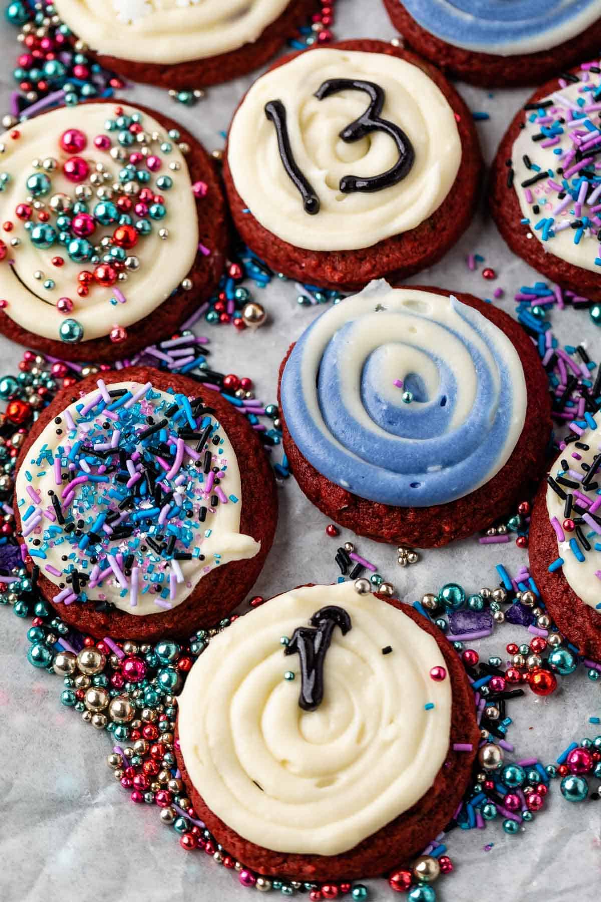 red velvet cookies with white frosting and blue and purple toppings