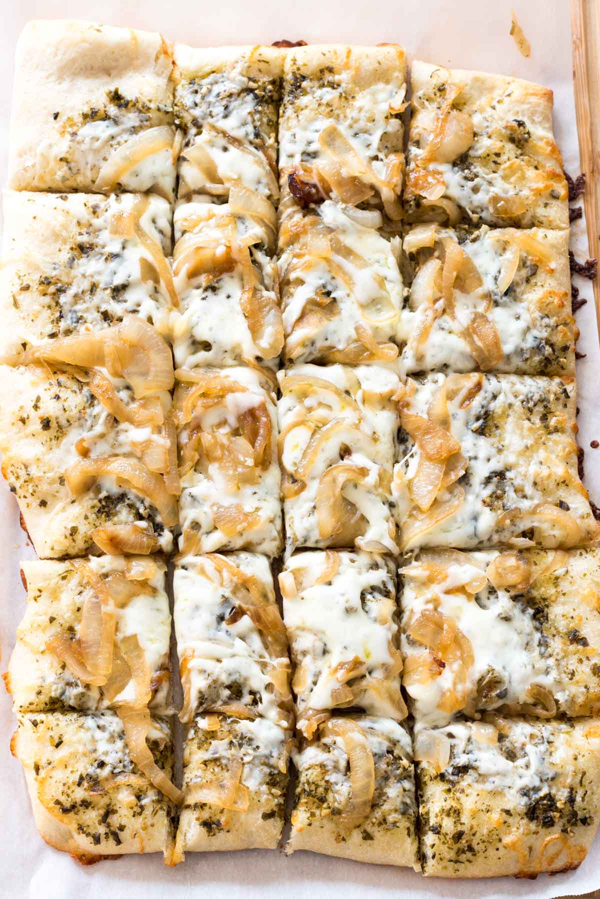 flatbread with onions and pesto on top laid out on a cutting board