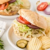 sandwich with lettuce tomatoes and chicken on a white plate.