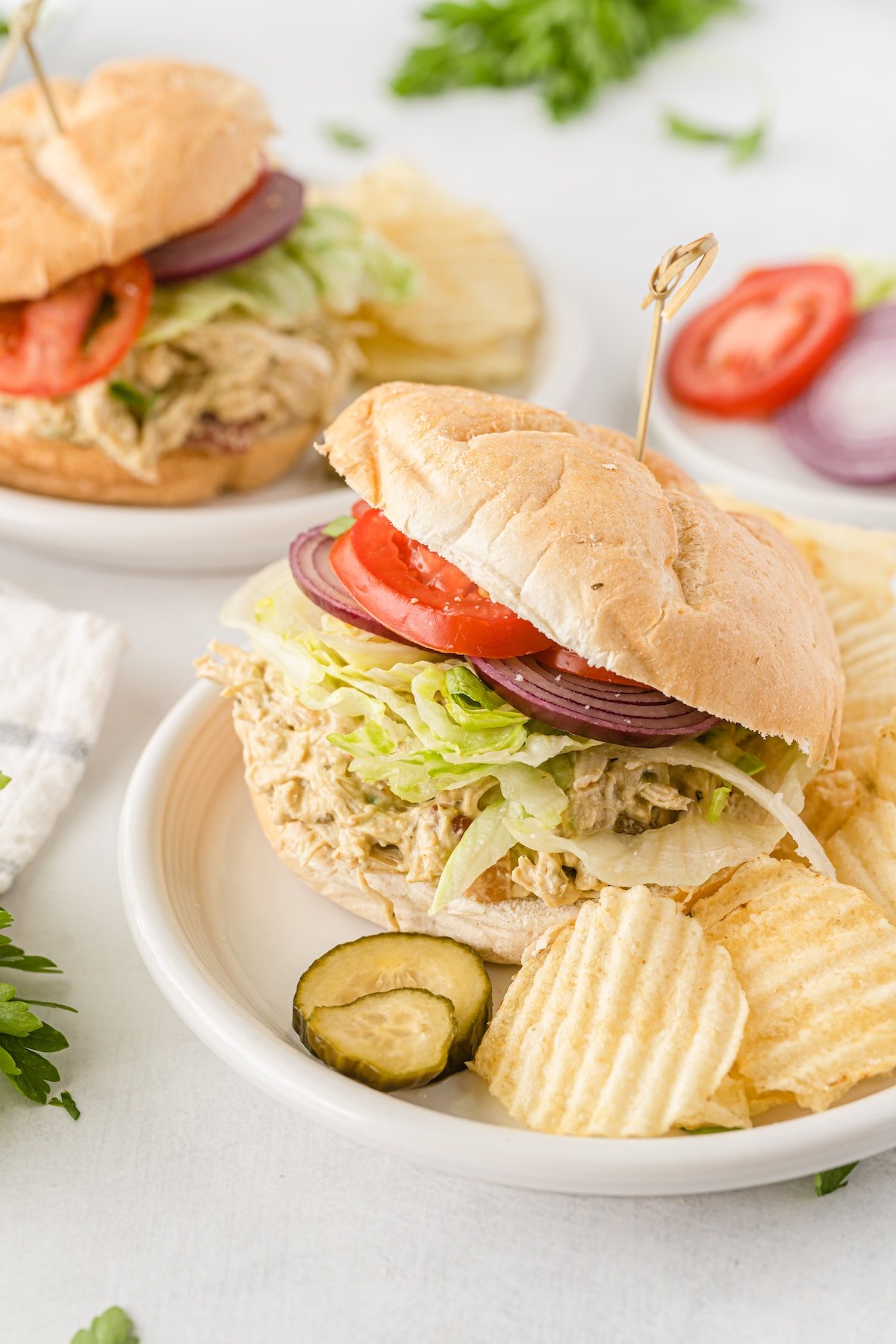 sandwich with lettuce tomatoes and chicken on a white plate.