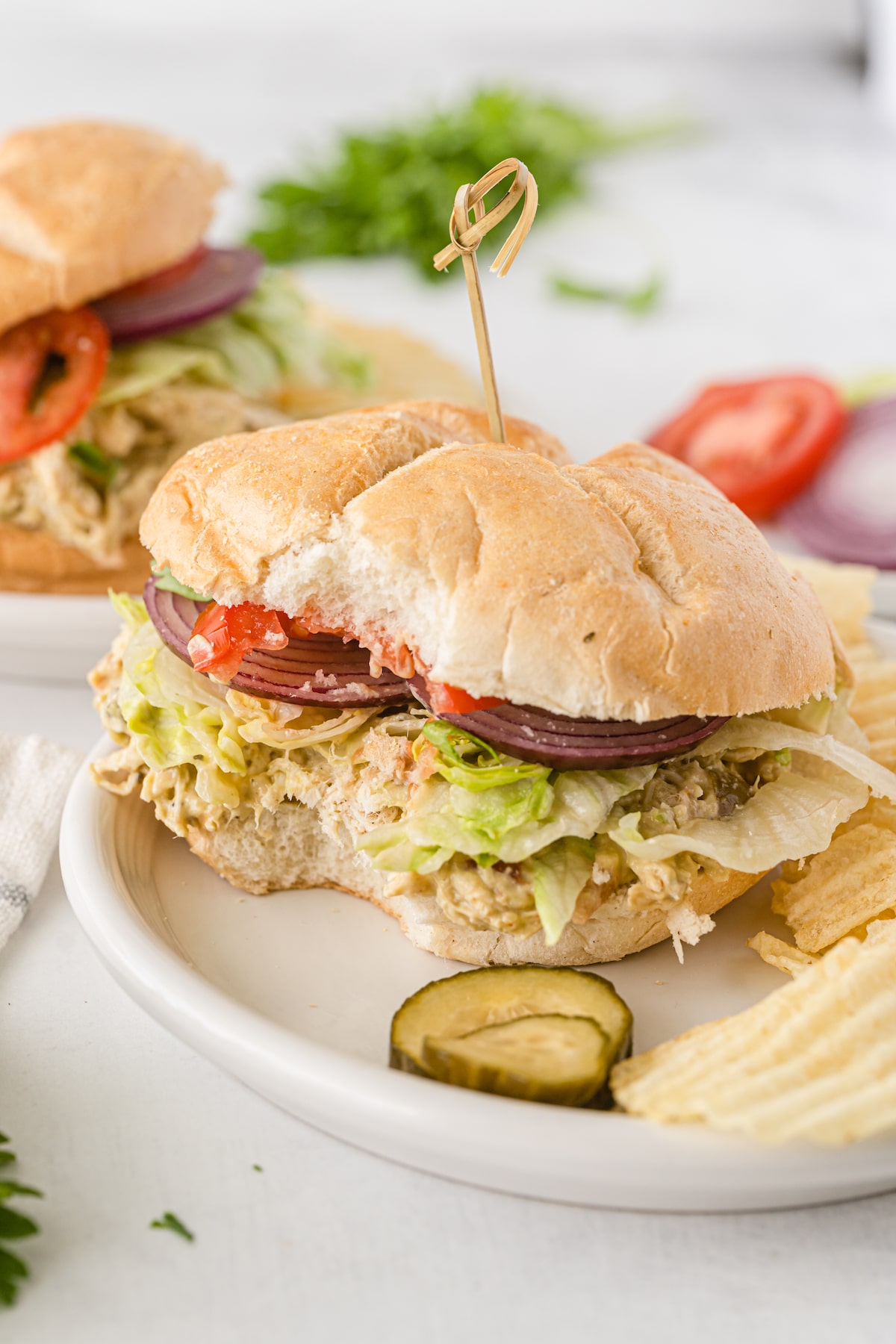 sandwich with lettuce tomatoes and chicken on a white plate.