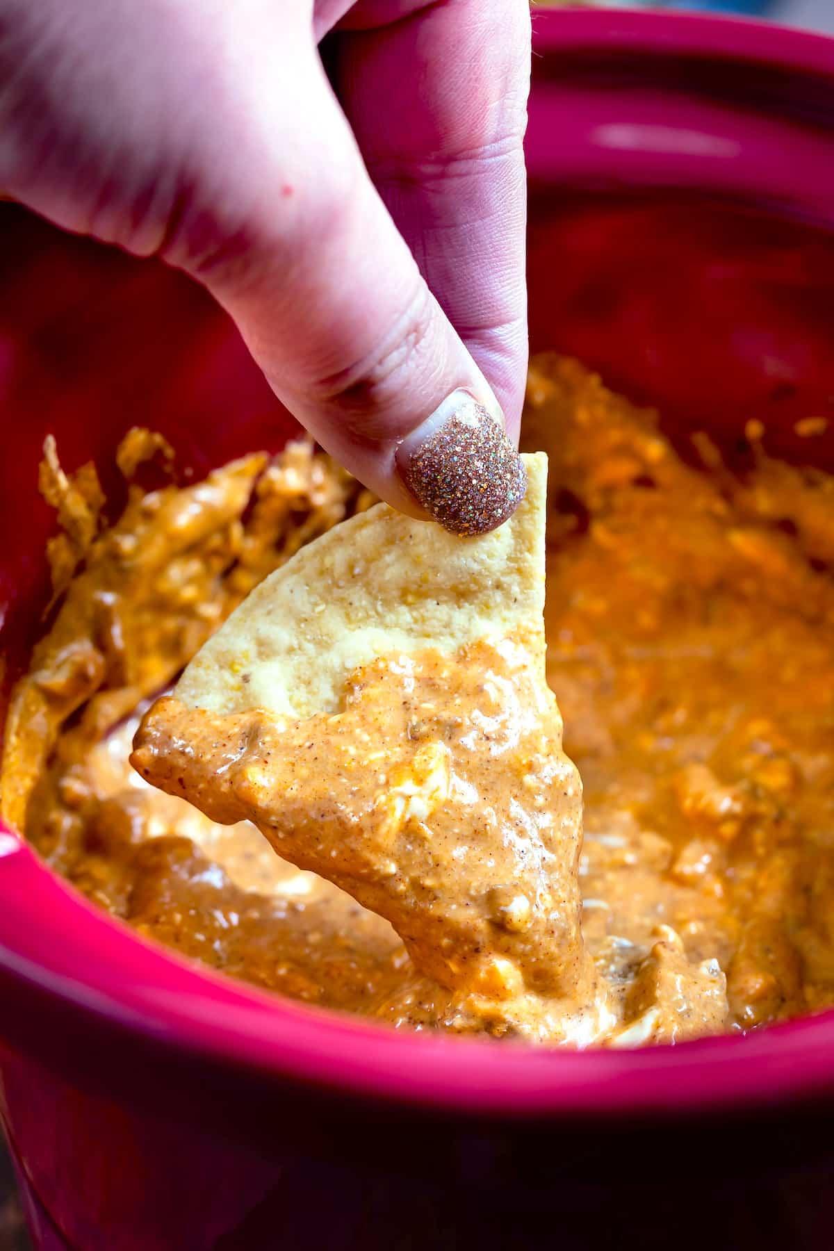 fingers holding chip in chili dip