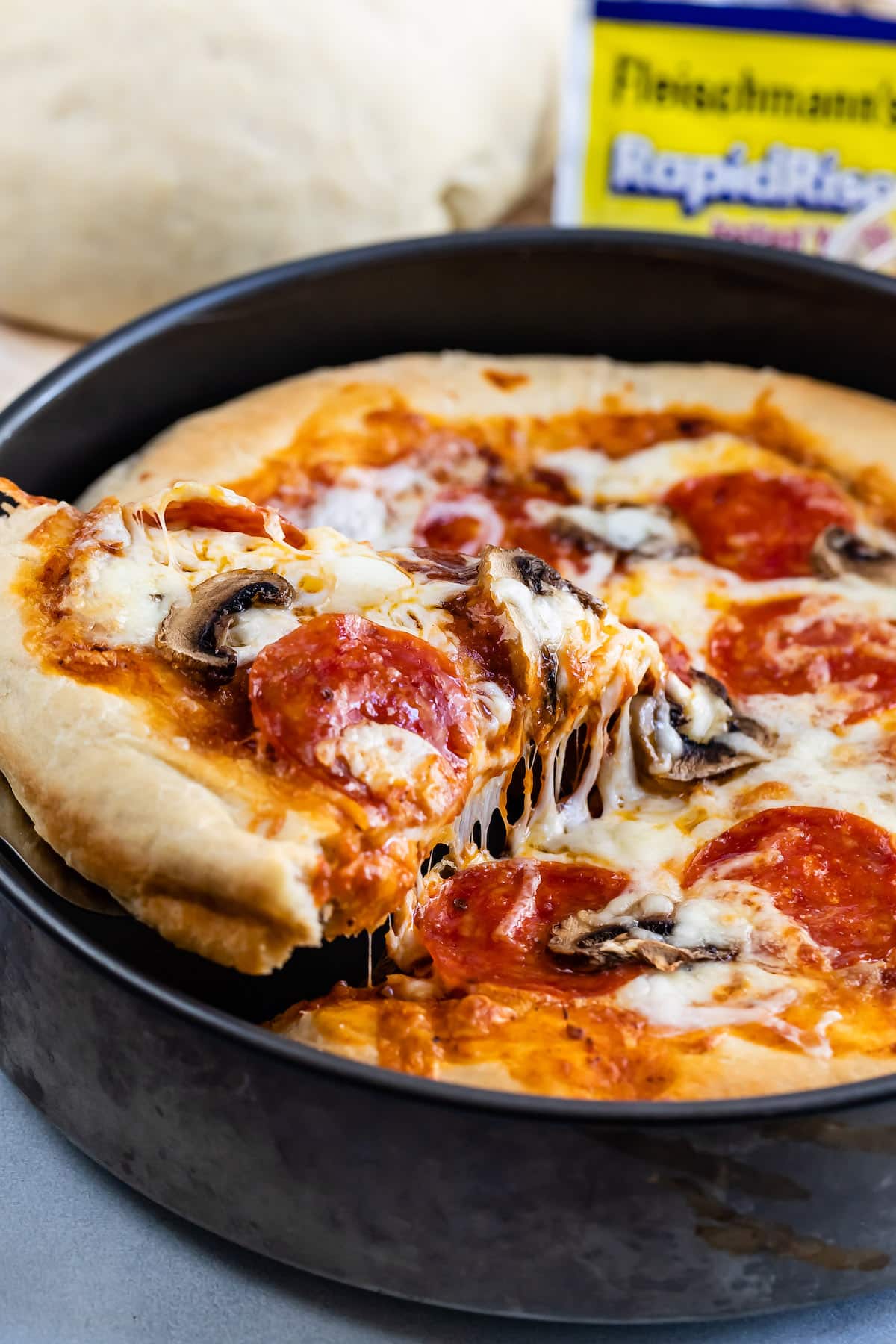 deep dish pizza in a black pan with pepperoni on top