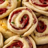 multiple pinwheels laid out on a dark cutting board with words on top