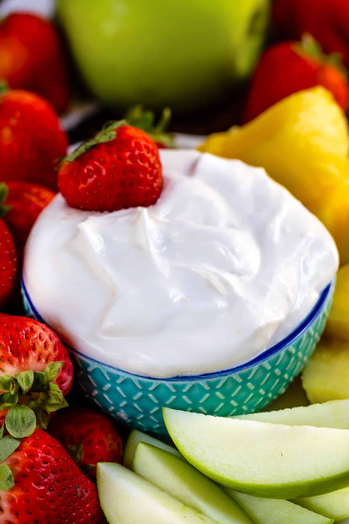 white fluff dip in a teal bowl surrounded by fruit