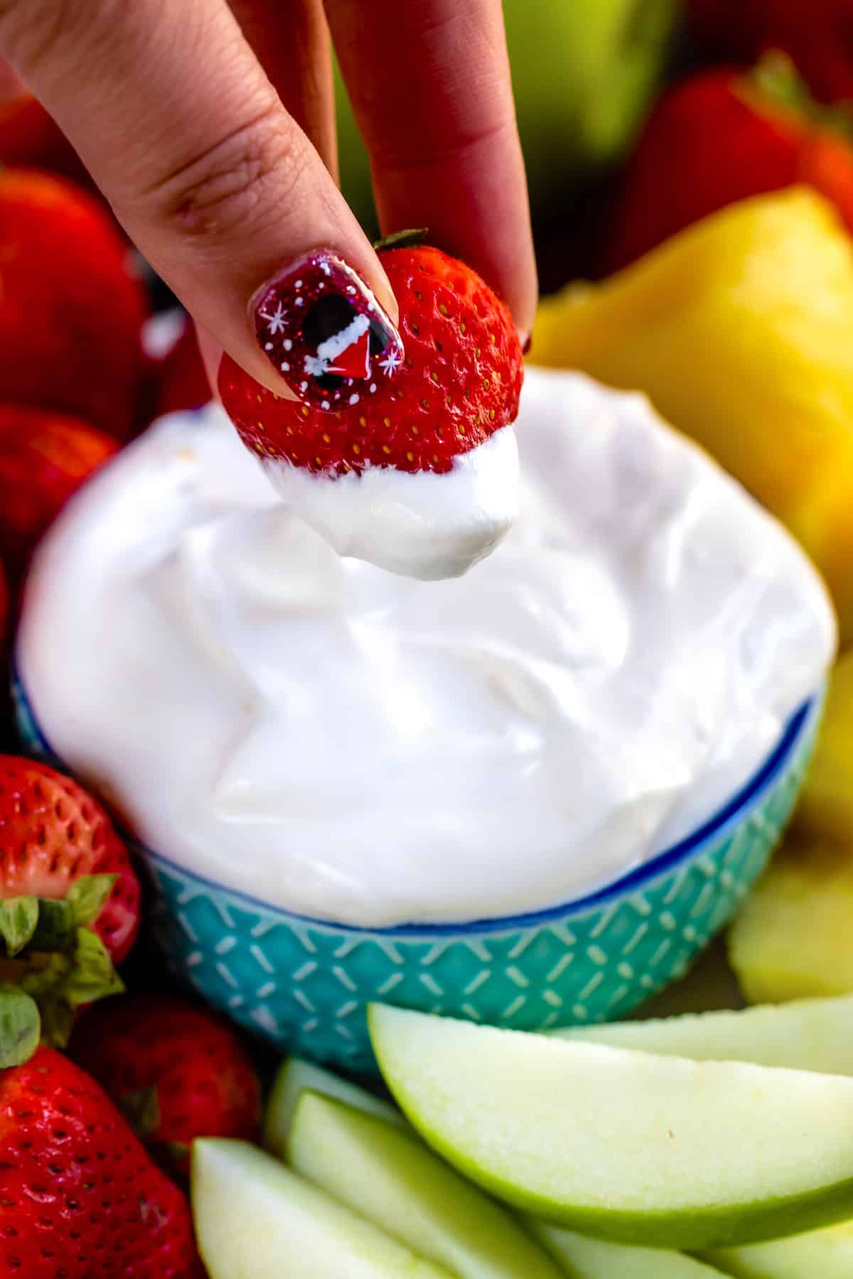 white fluff dip in a teal bowl surrounded by fruit