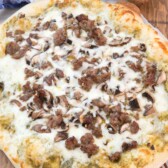 round pizza with sausage and white cheese on top