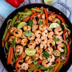 shrimp and limes and peppers mixed together in a black bowl