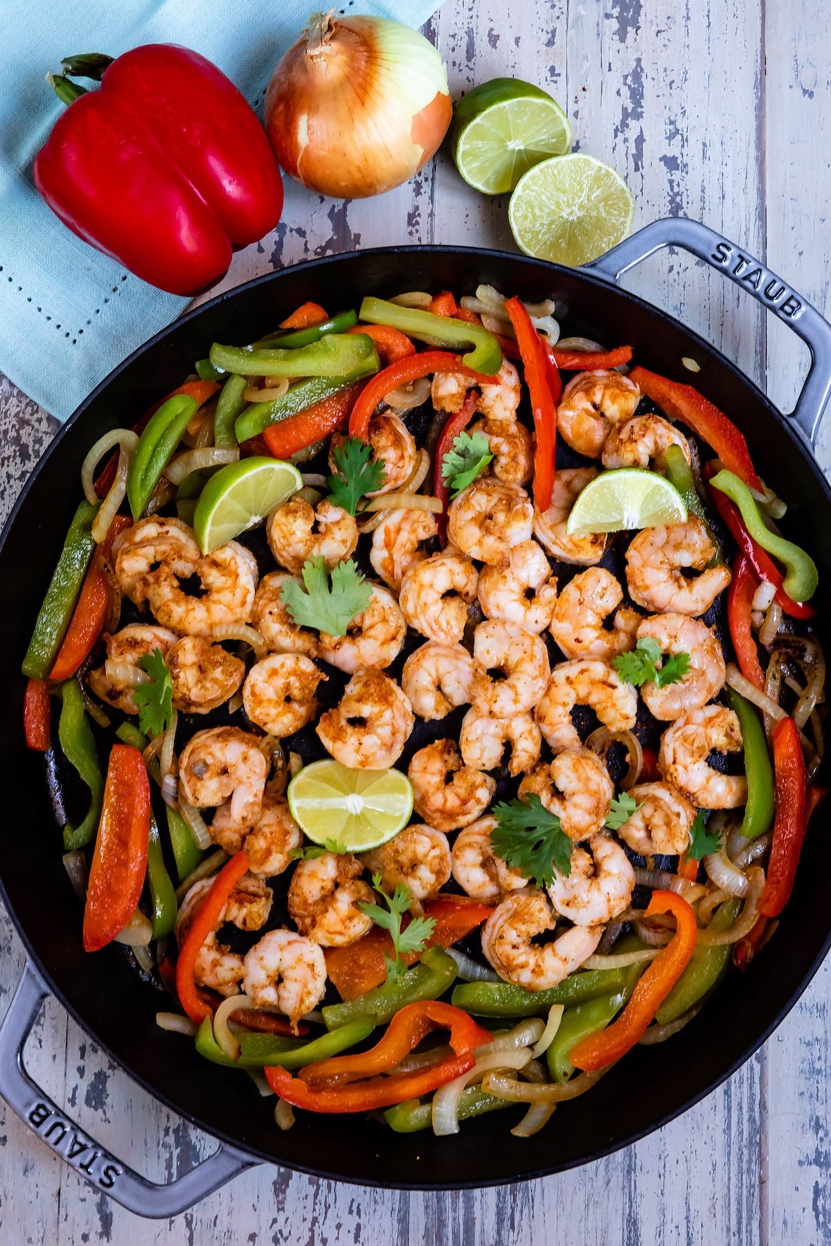 shrimp and limes and peppers mixed together in a black bowl