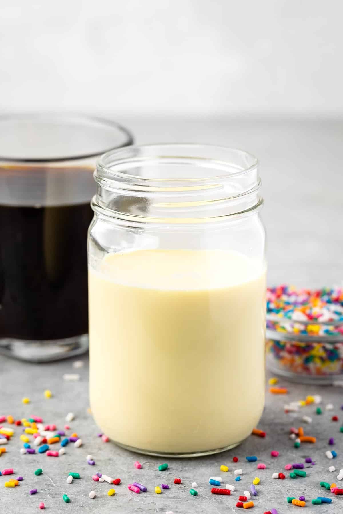 mason jar with creamer inside and sprinkles around the glass