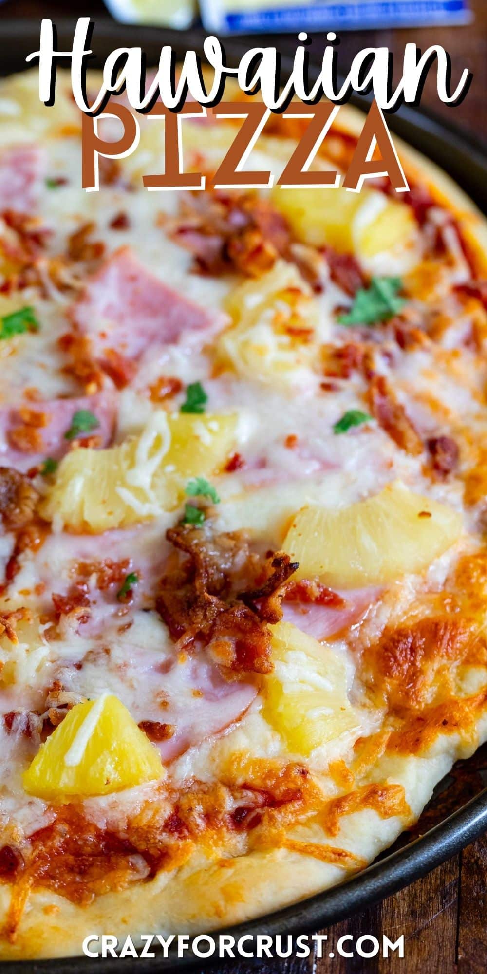 hawaiian pizza with ham and pineapple on top in a black pan with words on the image