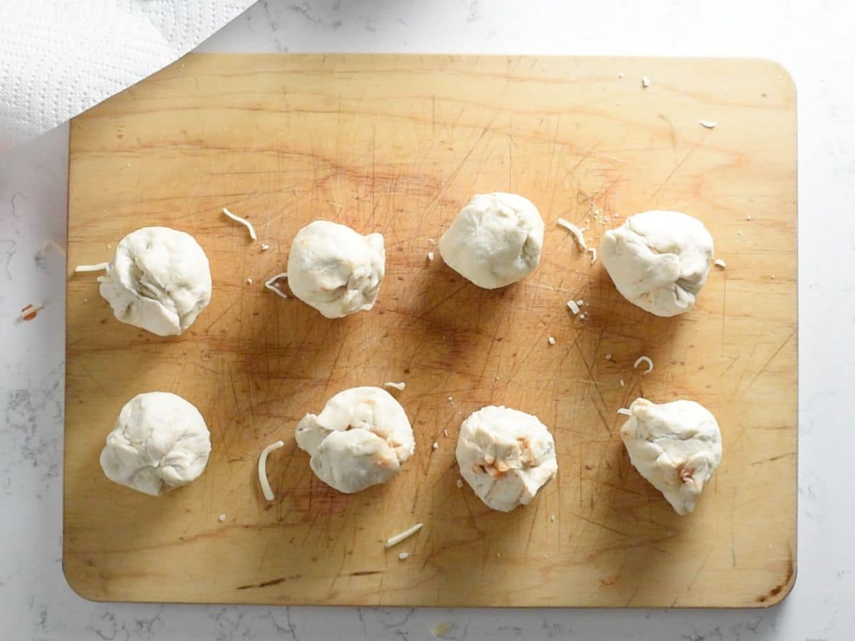 meatball sub bites rolled into balls on a cutting board.