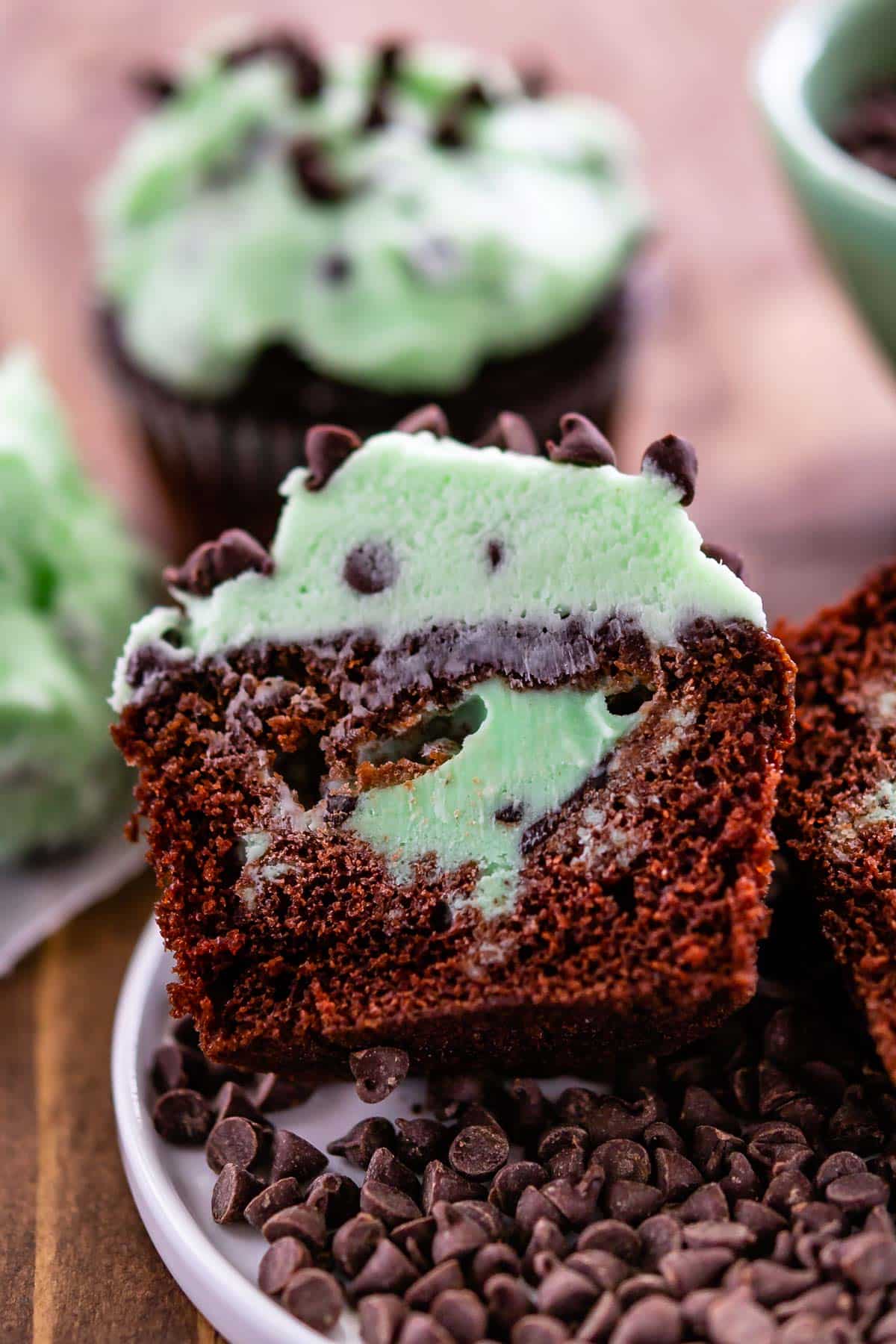 chocolate cupcakes with green mint frosting on top and in the center of the cupcake.