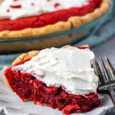 one slice of red velvet pie with white frosting on top on a grey plate