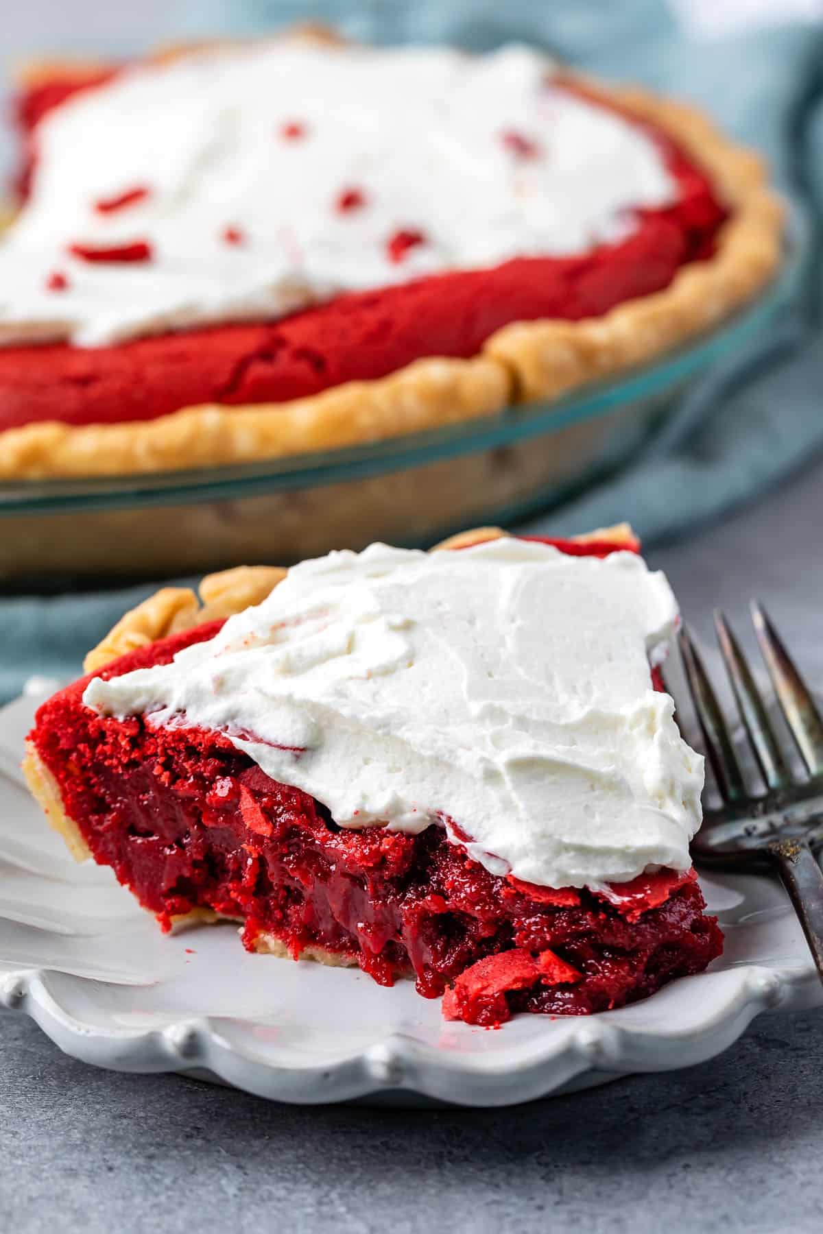 one slice of red velvet pie with white frosting on top on a grey plate