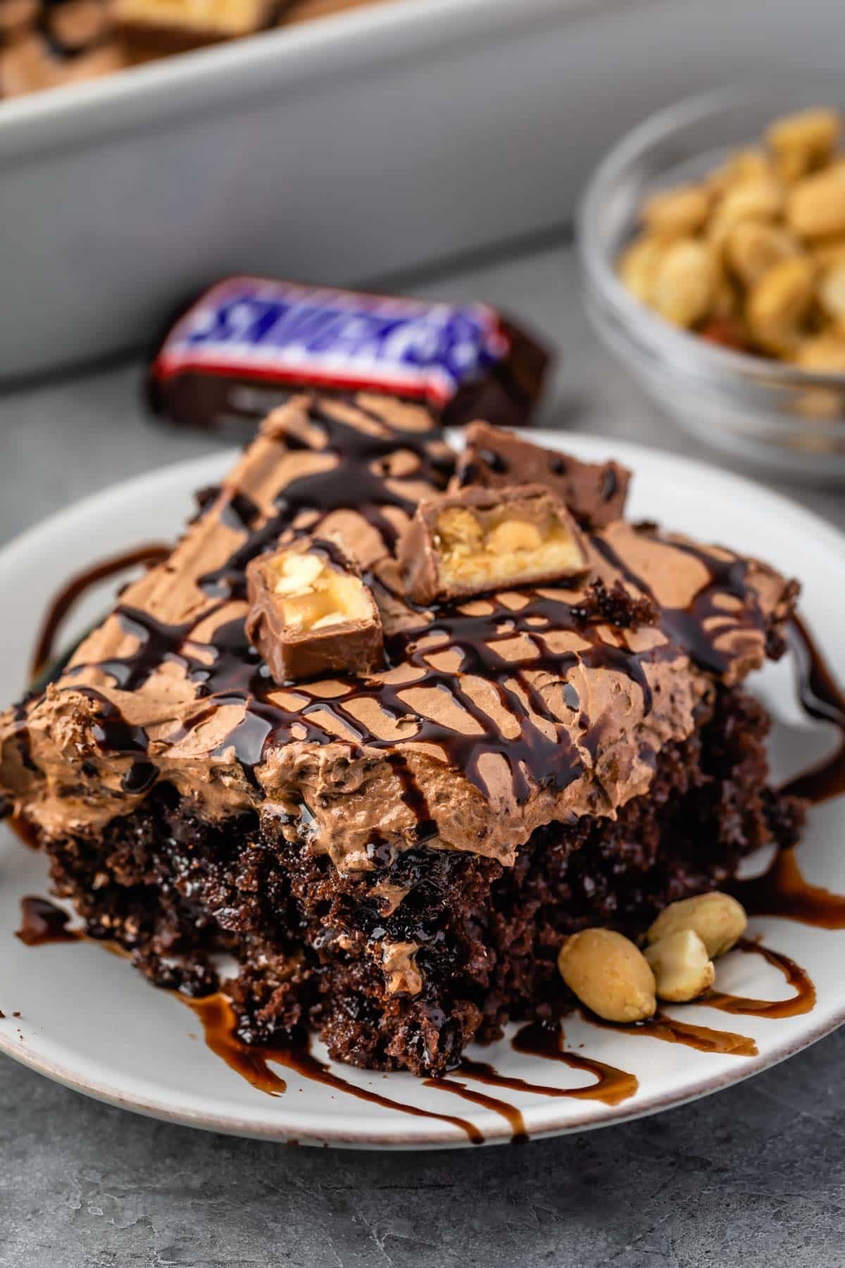 one square slice of snickers poke cake on a white plate