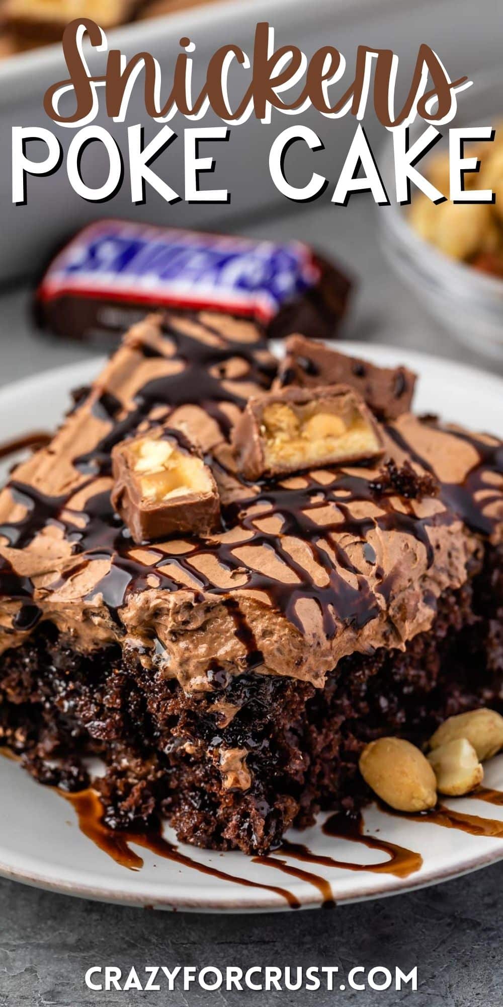 one square slice of snickers poke cake on a white plate with words on the image