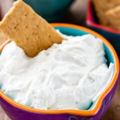white dip in a purple bowl with a cracker in it