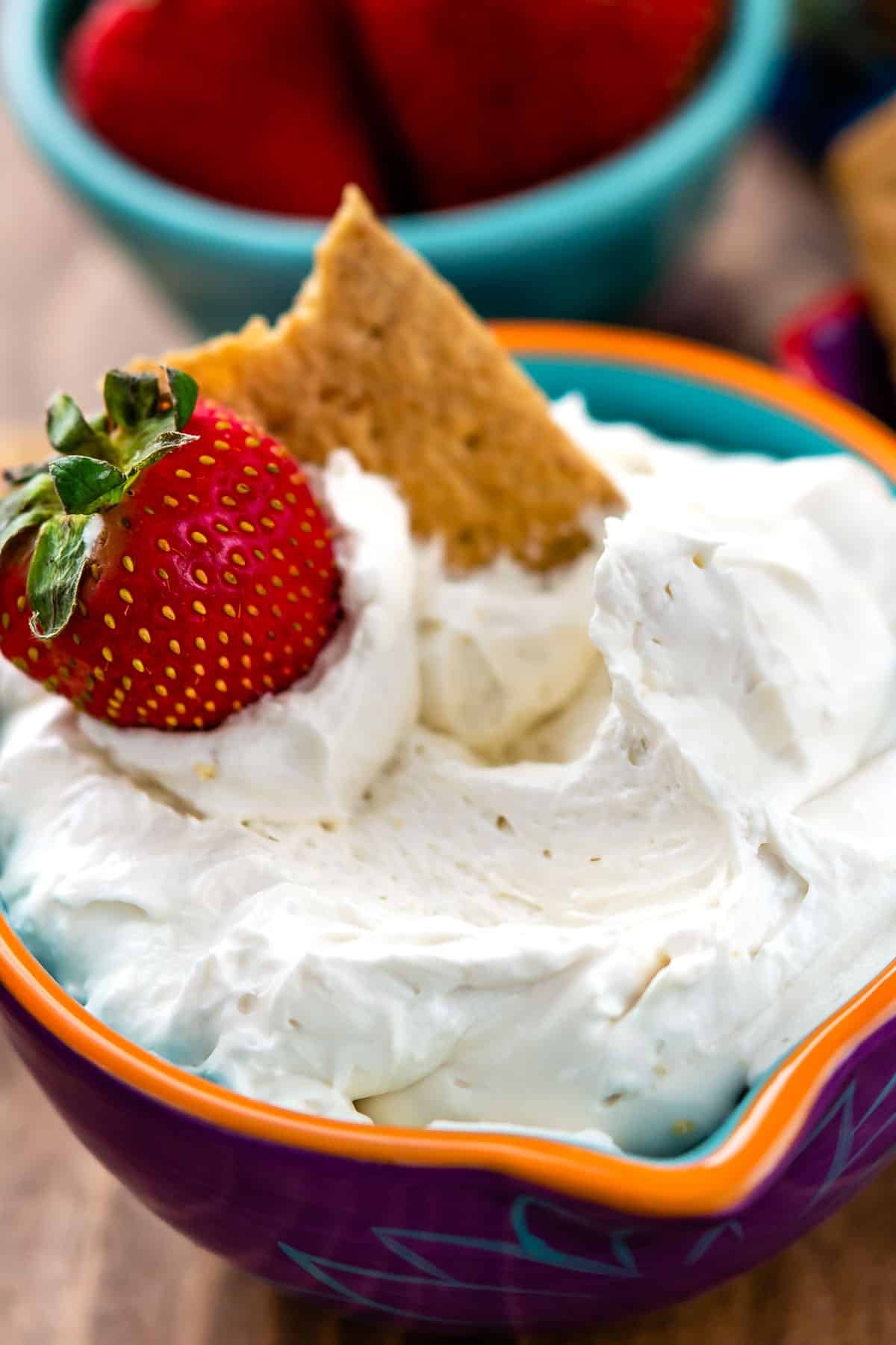 white dip in a purple bowl with strawberries on top