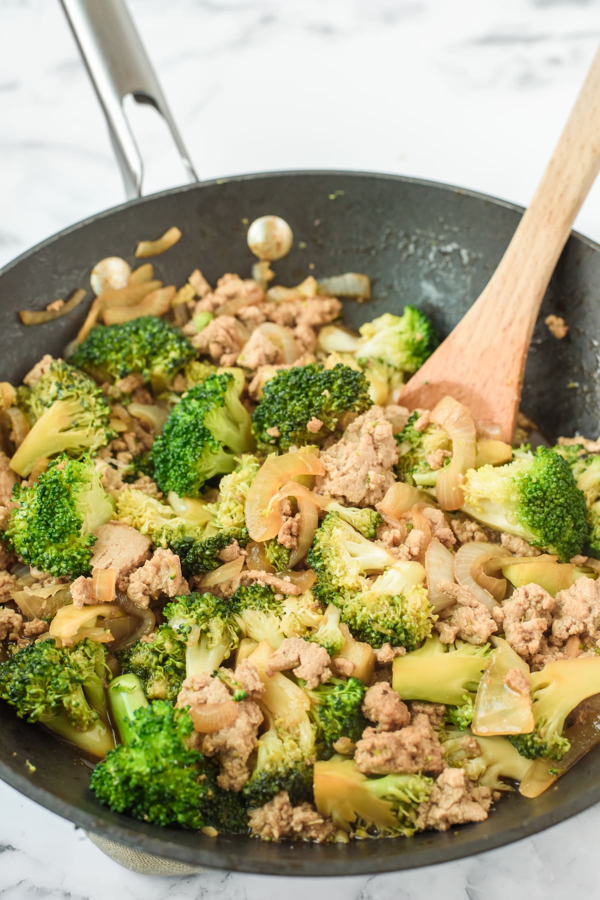 broccoli and meat mixed together in a black pan