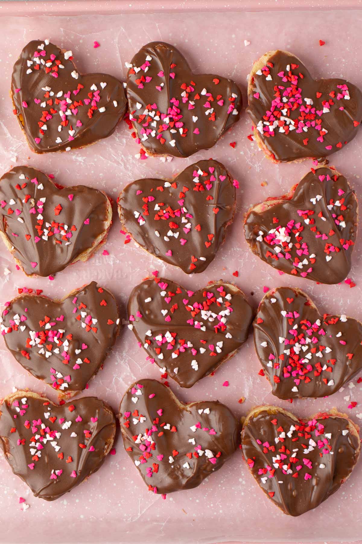 heart shaped sugar cookies with chocolate frosting and red sprinkles on top