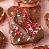 heart shaped sugar cookies with chocolate frosting and red sprinkles on top
