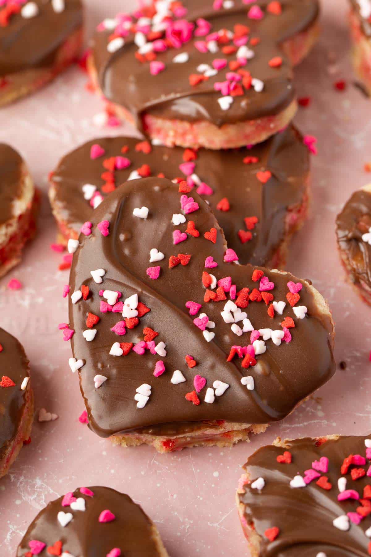 heart shaped sugar cookies with chocolate frosting and red sprinkles on top