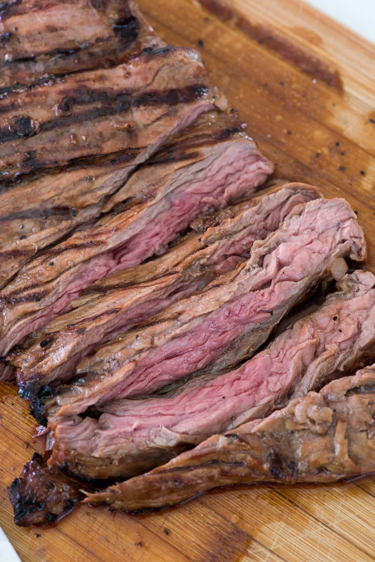 steak sliced onto a wooden cutting board.